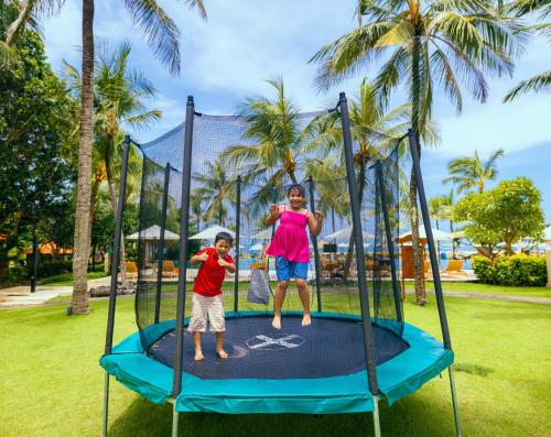 two children are playing on a trampoline at The Ayodya Palace in Nusa Dua