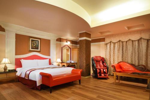 a hotel room with a bed and a red chair at Natoli Motel in Tainan