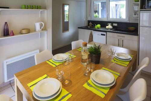 a kitchen with a wooden table with yellow and white dishes on it at Holiday resort Normandie Forges les Eaux Apartment for 5 pers in Forges-les-Eaux