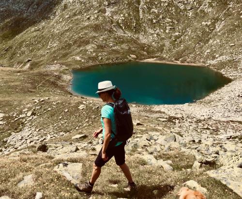 a man with a backpack walking on a mountain with a blue lake at Nanisgarten - Grannys flat in Obergesteln