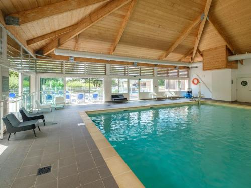 une piscine intérieure avec des chaises bleues et un plafond dans l'établissement Holiday home Club Le Domaine Du Golf 1, à Saint-Hilaire-Saint-Florent