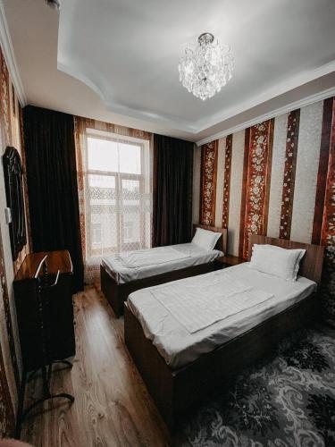 a bedroom with two beds and a chandelier at Гостевой дом Рамазан-отель in Taraz
