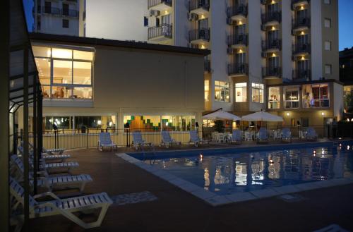 um hotel com uma piscina com cadeiras e edifícios em Hotel Plaza em Lido degli Estensi