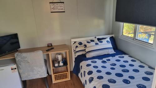a small bedroom with a bed and a television at Linga Longa Spiritual Retreat in Curra