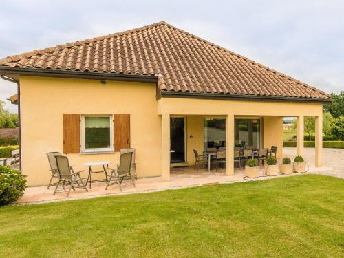 une maison avec des chaises et des tables dans une cour dans l'établissement Modern holiday home in Aquitaine, à Saint-Nexans