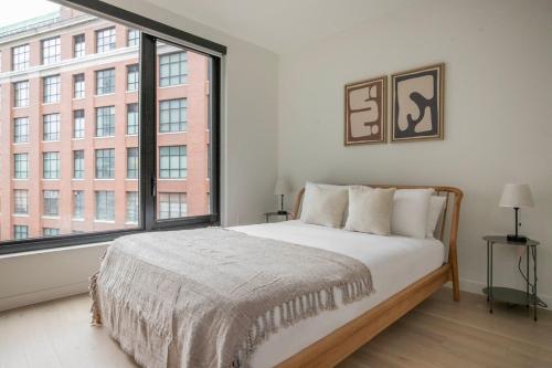 ein Schlafzimmer mit einem Bett und einem großen Fenster in der Unterkunft Blueground South Boston gym near T shops BOS-1024 in Boston