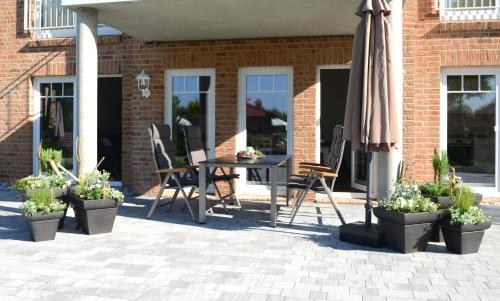 a patio with a table and chairs and an umbrella at Villa Kanalblick, Schiffsdeck in Oldenbüttel