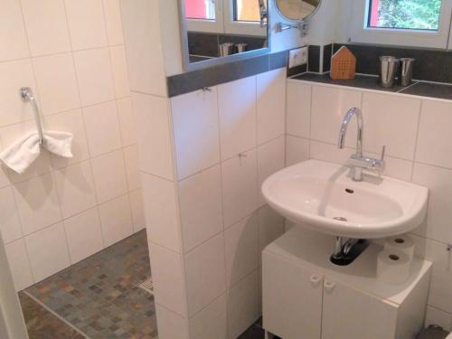W białej łazience znajduje się umywalka i lustro. w obiekcie Pine cones in the Haslehaus w mieście Feldberg