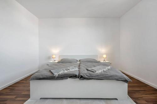a bed in a white room with two lamps at Casa Bergblick in Bickenbach