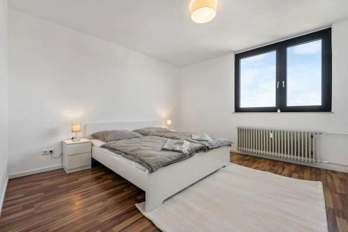 a white bedroom with a bed and a window at Casa Bergblick in Bickenbach