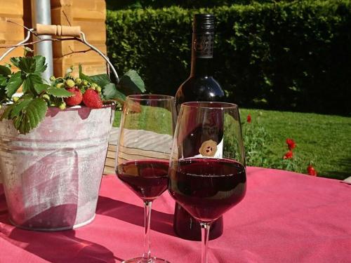 two glasses of wine on a table with a bottle of wine at Holiday home our little hunting lodge in Philippsreut