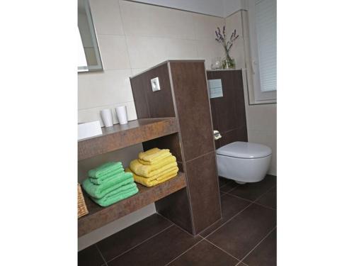 La salle de bains est pourvue de toilettes et de serviettes sur une étagère. dans l'établissement Holiday apartment Seimbergblick, à Brotterode