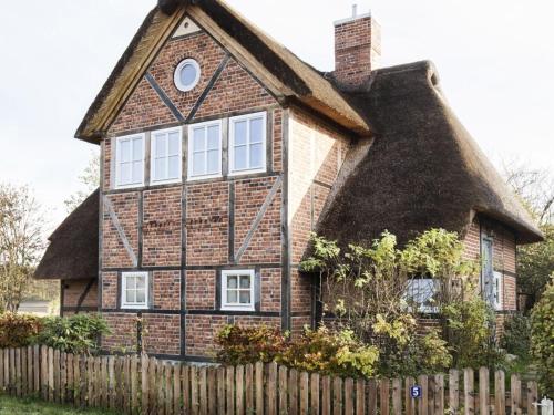 a thatched house with a fence in front of it at Holiday home Kate keit in Altenhof