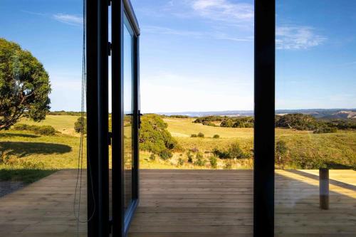 a glass door of a house with a view of a field at Sky Ship 1 - Luxury Off-Grid Eco Accommodation in Cape Otway