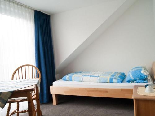 - une chambre avec un lit avec des rideaux bleus et une table dans l'établissement Holiday apartment B in Haus Seewind, à Wittdün