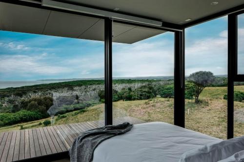 a bedroom with a bed and a balcony with a view at Sky Pod 2 - Luxury Off-Grid Eco Accomodation in Cape Otway