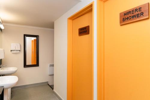 a bathroom with an orange door with a fire shower sign at Haka Lodge Queenstown in Queenstown