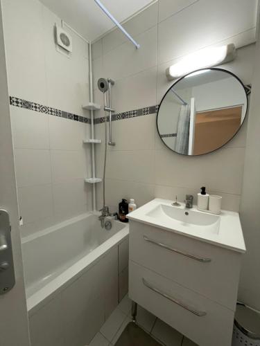 ein weißes Badezimmer mit einem Waschbecken und einem Spiegel in der Unterkunft Bel appartement tout confort aux Portes de Paris in Cergy