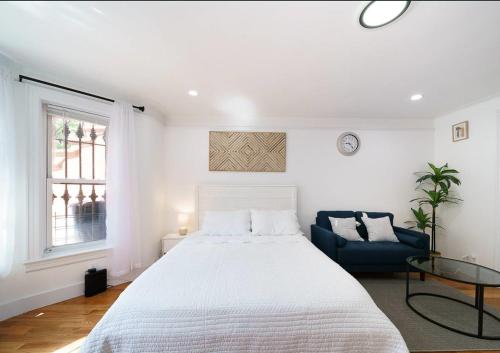 a white bedroom with a large bed and a blue couch at Comfy Studio in UES! Perfect for 2! in New York