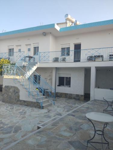 a building with stairs and a table in front of it at Akrotiri rooms in Nea Mesangala