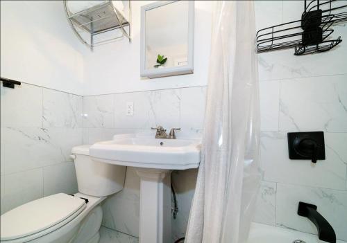 a white bathroom with a toilet and a sink at Comfy Studio in UES! Perfect for 2! in New York