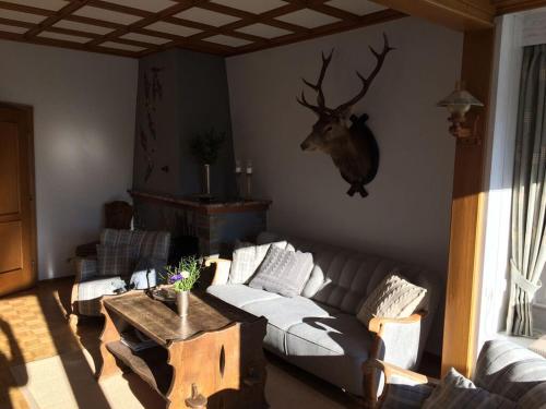 a living room with a couch and a deer head on the wall at Holiday home Waldhaus am Burbach in Bad Berleburg