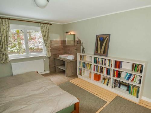 een slaapkamer met een bed en een boekenplank met boeken bij Holiday home Waldhaus am Burbach in Bad Berleburg