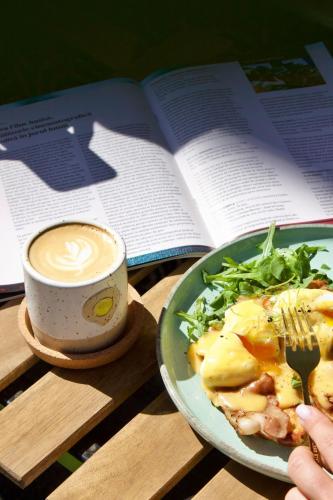 a plate of food and a cup of coffee and a book at Townhouse Boutique in Sibiu
