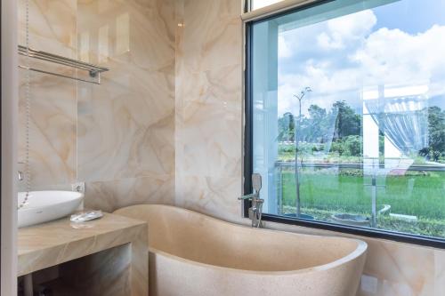 une salle de bain avec baignoire et une grande fenêtre dans l'établissement TwoSpaces Living at deRos Resort & Cafe, Bogor, à Ciherangsating
