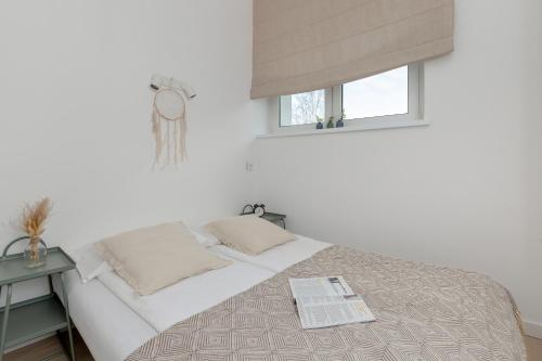 a white bedroom with a bed with a window at Apartments Łagiewniki Gdańsk by Renters in Gdańsk