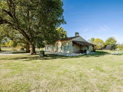 ein altes Haus auf einem Feld mit einem Baum in der Unterkunft Spacious Holiday Home in Saint Nexans with Terrace in Saint-Nexans
