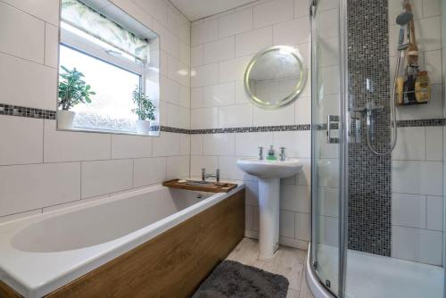 een badkamer met een bad, een wastafel en een douche bij Rhianfa Manorbier in Manorbier
