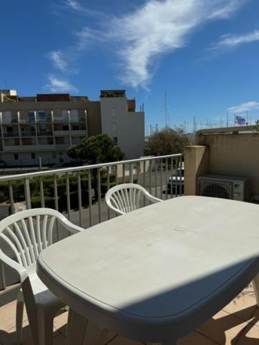 einen weißen Tisch und zwei Stühle auf dem Balkon in der Unterkunft Appartement climatisé avec grande terrasse SUD in Gruissan