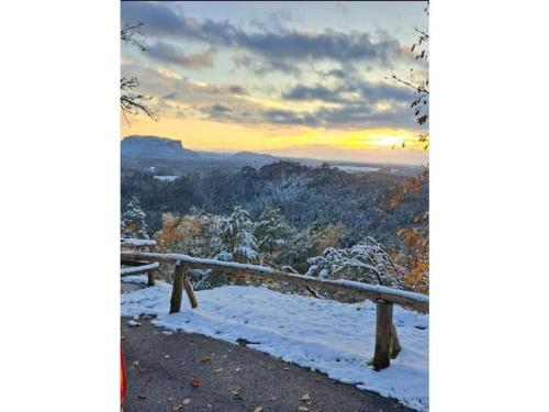 a bench in the snow with a sunset in the background at on the edge of town Comfortable Vacation Home in Bad Schandau