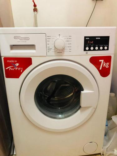 a white washing machine with red labels on it at Room center in Muscat