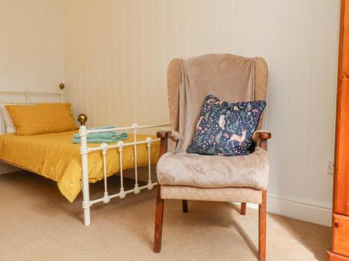 a bedroom with a chair and a bed with a pillow at Bousdale Cottage in Guisborough