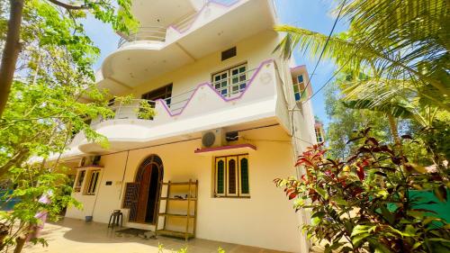 a white house with a balcony and trees at Lotus Garden - Near Matrimandir Center Auroville in Auroville