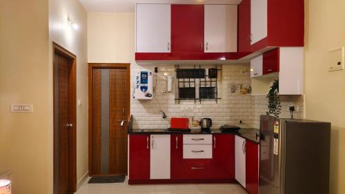 a kitchen with red and white cabinets and a refrigerator at 2390 Home Tales by Tipiverse, HSR Layout in Bengaluru