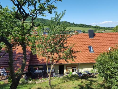 a house with an orange roof and some trees at Charming holiday home with natural garden in Kaltennordheim Thuringia in Unterweid
