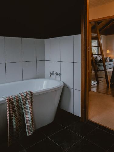 a white bath tub in a bathroom with white tiles at Sunken Sea Shack - waterfront getaway in Eggs and Bacon Bay