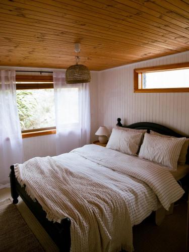 a bedroom with a large bed with a wooden ceiling at Sunken Sea Shack - waterfront getaway in Eggs and Bacon Bay