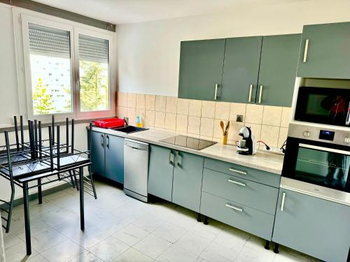 uma cozinha com armários azuis e um forno com placa de fogão em Superbe T2, Spacieux em Saint-Étienne