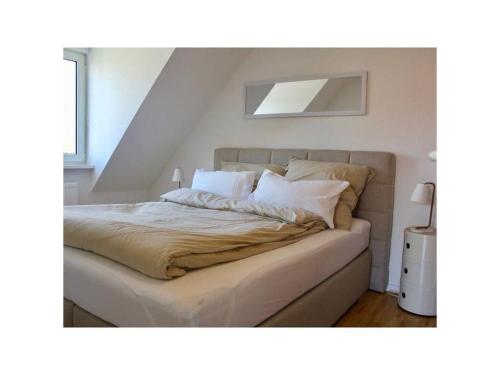 Una cama con sábanas blancas y almohadas en un dormitorio en Schönhier-Vimmendorf, en Timmendorfer Strand