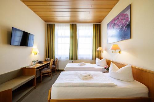a hotel room with two beds and a desk at Flair Hotel Kamenz in Kamenz