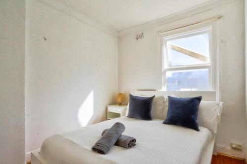 Un dormitorio con una cama con almohadas azules y una ventana en Delightful 2 Bedroom House Pyrmont 2 E-Bikes Included, en Sídney