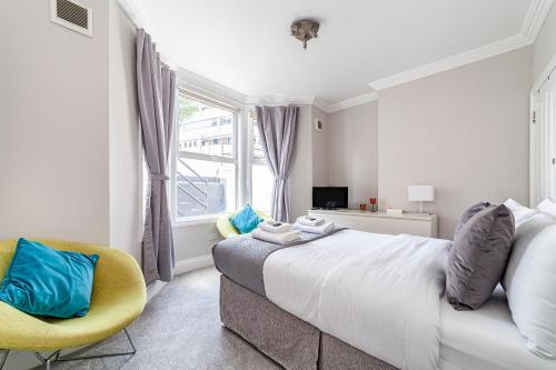 a bedroom with a large bed and a yellow chair at Amazing 2BR flat wprivate garden, Maida Vale in London