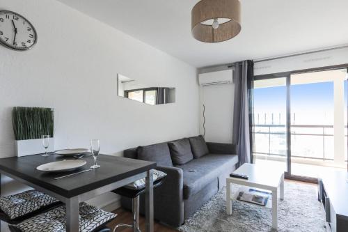 ein Wohnzimmer mit einem Sofa und einem Tisch in der Unterkunft Appartement Tavernia - Welkeys in Mandelieu-la-Napoule