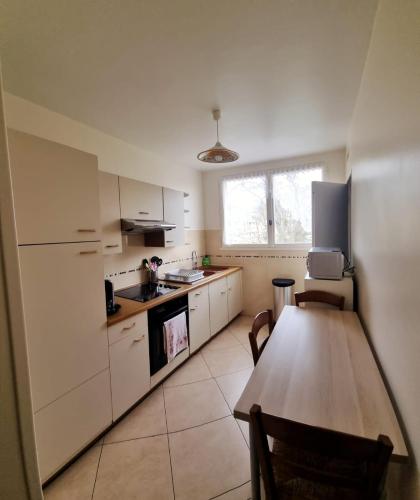 uma cozinha com armários brancos e uma mesa de madeira em Chambre à 20 min de Paris em Crosne