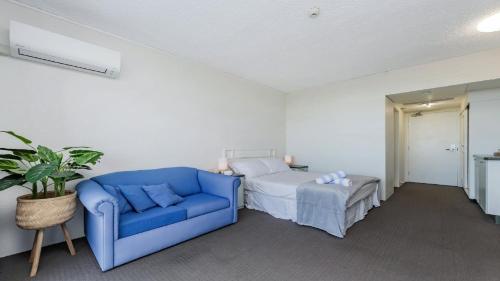 a bedroom with a blue couch and a bed at Studio 211 - Seaside Serenity Your Perfect Retreat in North Ward