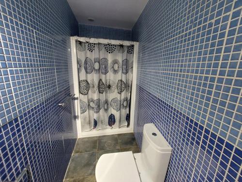 a blue tiled bathroom with a toilet and a window at Lanzarote Hostel in Arrecife